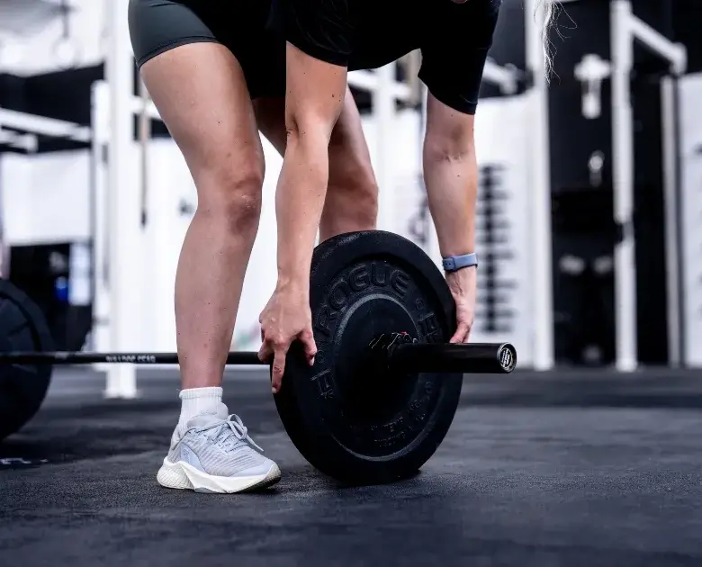 Member adjusting a barbell during a training session at Troy City Fitness