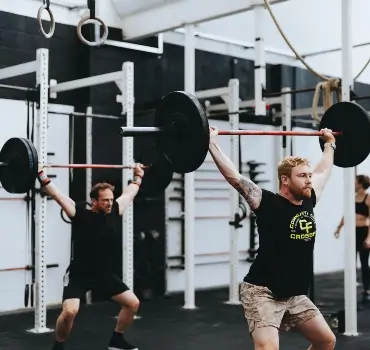 Two members doing an overhead barbell lift at Troy City Fitness